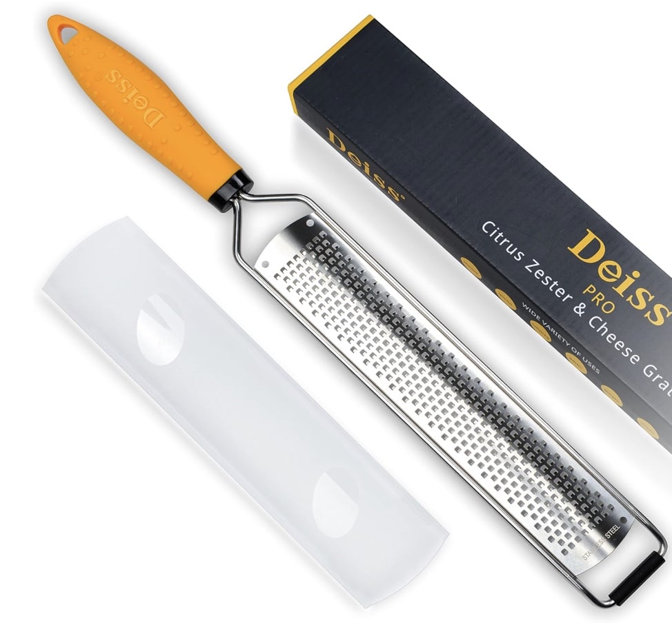 A citrus zester and cheese grater with an orange handle, a protective cover, and its black and yellow packaging labeled "Deiss PRO"—perfect for adding zest to your favorite flower cookies recipe.